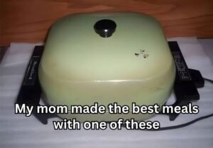 Vintage electric skillet, light green, with a black knob and legs, on a white surface